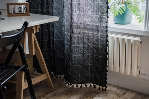 Détail du rideau noir à motif géométrique avec pompons et texture en coton et lin