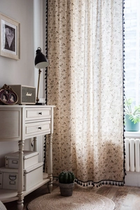 Detailed close-up of linen curtain with dandelion print and black fringe tassel trim