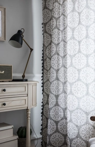 Vue détaillée du rideau gris avec imprimé mandala et franges à pompons noirs