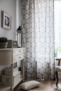Détail du rideau en lin gris avec motif mandala et bordures à pompons noirs de style rétro