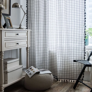 Modern white grid curtains with black tassel trim in a cozy minimalist living room setup