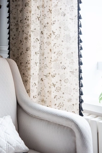 Detailed close-up of cotton linen curtain with floral dragonfly print and dark blue tassels