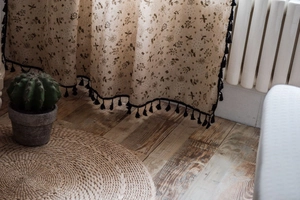 Close-up of cotton linen curtain with dandelion print and black tassel trim detail