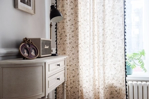 Detailed view of dandelion floral print curtains with decorative black pompom fringe trim