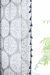 Détail du rideau en coton et lin gris à motif mandala avec franges à pompons noirs