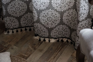 Détail de rideau en coton lin gris avec imprimé mandala blanc et bordure à pompons noirs