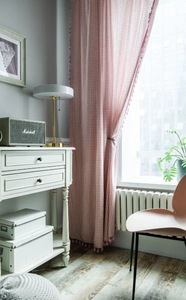 Detailed close-up of pink checkered cotton linen curtain with tassel fringe decoration