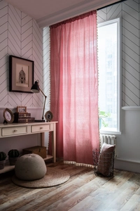 Close-up of red gingham curtains with beige tassel fringe detail in a cozy home setting