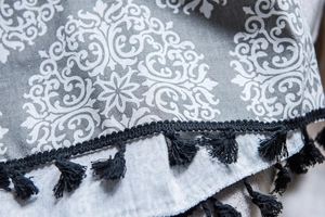 Gros plan sur tissu en lin gris avec motif damassé blanc et bordure à franges noires