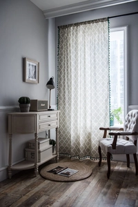 Detail view of cotton linen curtain with geometric diamond patterns and green tassel fringe