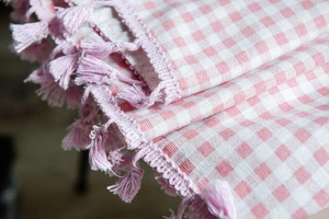 Detail of pink and white gingham cotton linen fabric with delicate tassel fringes