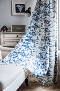 Detail of blue Toile de Jouy printed cotton linen curtain with elegant cream tassels