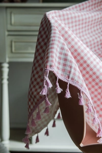 Detailed view of pink gingham linen curtain with decorative pom-pom fringe edges