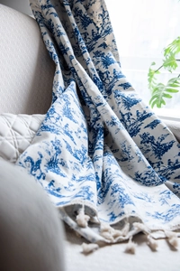 Detail of blue Toile de Jouy printed cotton linen curtain with beige tassel fringe