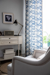 Detail of blue and white Toile de Jouy curtains with elegant tassel fringe and floral pattern
