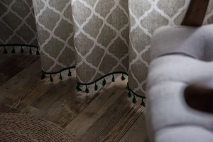 Detail view of cotton linen curtain with green clover pattern and fringe tassels edge