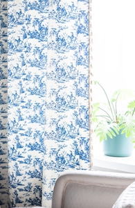 Detail of blue Toile de Jouy pattern on cotton linen curtain with beige tassel trim
