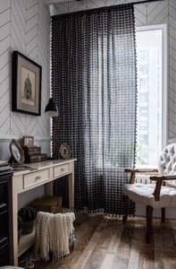 Detailed close-up of black and white grid curtain with elegant pom-pom fringe edges