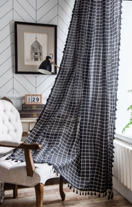 Detail of black and white plaid curtain fabric with black tassel trim on the edge