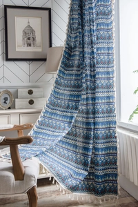 Detail of bohemian geometric blue cotton linen curtain fabric with cream tassel fringe