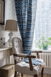Close-up of geometric blue bohemian curtain fabric featuring decorative beige tassels