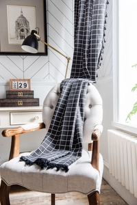 Detail of black grid cotton linen curtain with elegant tassels in a Nordic interior setup