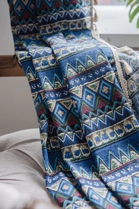 Close-up of geometric knit fabric with ethnic patterns and decorative cream tassels