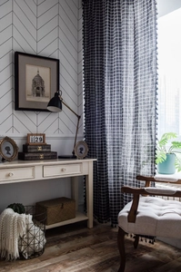 Close-up of black and white checkered linen curtain with elegant fringe ball trim