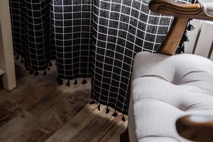 Detailed close-up of black and white checkered linen curtain with decorative black tassels