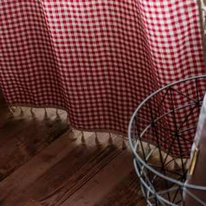 Red and white checkered curtain with cream fringe tassels in a cozy farmhouse style