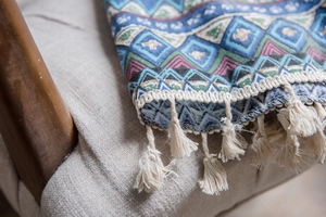 Detailed macro view of bohemian geometric pattern fabric with creamy white fringe tassels