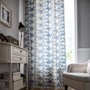 Blue Toile de Jouy print linen curtains with tassel edges in a rustic French country style