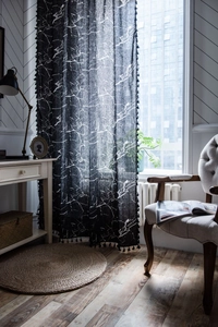 Detail of black marble print curtain with small fringe tassels and semi-sheer fabric
