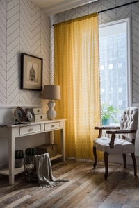 Detailed close-up of yellow geometric pattern fabric and white tassel fringe trim