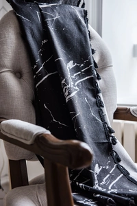Detail of black marble print fabric with elegant fringe tassels on an armchair