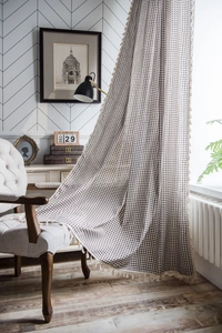 Dettaglio di tenda in lino a quadretti marroni con nappe beige in stile retrò