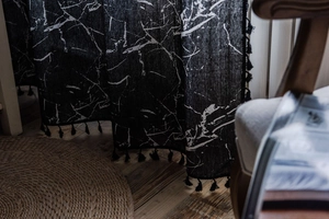 Detail of black marble print curtain fabric featuring decorative tassel trim at the bottom