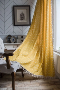 Detail of yellow geometric pattern curtain with white decorative tassel fringe trim
