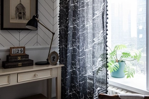 Detail of black marble print curtain with elegant tassel fringe in a cozy home setting