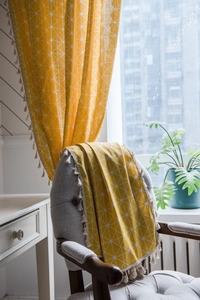 Detail of yellow geometric pattern fabric with white pom-pom tassels for home decor