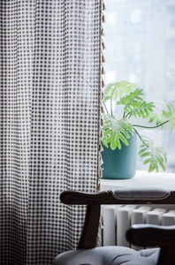 Dettaglio della tenda a quadretti marroni e bianchi con bordi decorativi di nappe
