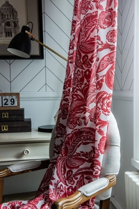 Detail of red Baroque floral cotton linen fabric draped on a chair with retro decor