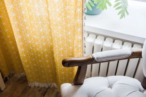 Detailed close-up of yellow geometric cotton linen curtain with decorative tassels