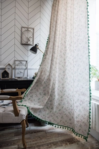 Detail of floral printed cotton curtain featuring decorative green pom-pom fringe trim