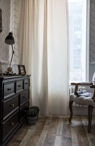 Detailed texture of cotton linen curtain with delicate white lace trim in natural light
