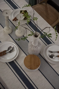 Detail of cream linen tablecloth with navy blue stripes in a minimalist table setting