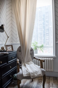 Detail of elegant lace border on creamy cotton linen curtain with vintage texture