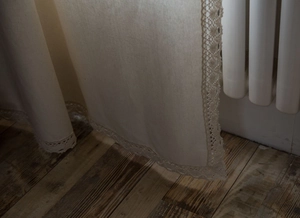 Detailed macro view of white lace trim on textured linen kitchen curtains