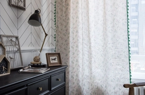 Detail of green tassel fringe and floral print on rustic cotton linen curtain fabric