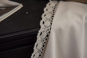 Detailed close-up of white lace curtain fabric with elegant hollow embroidery patterns